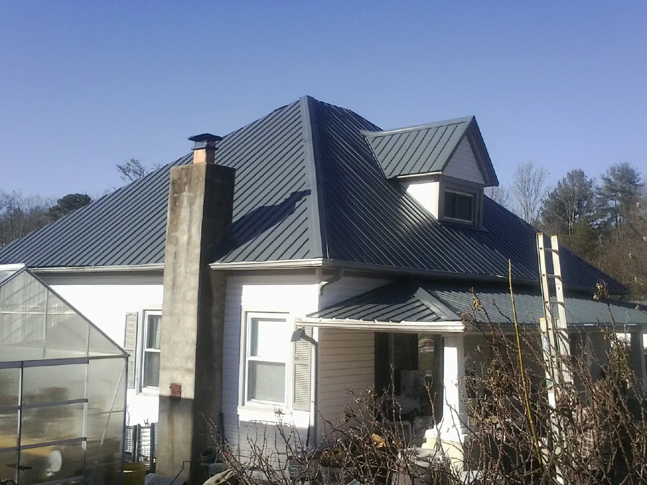 Dark blue standing seam metal roof on a white farmhouse with dormer — Slate & Tile Roof Repair by Roofing Brothers in Northvale