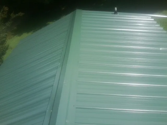 New green metal panels meeting at the ridge of a roof — Flat Roof Repair work by our crew in Northvale