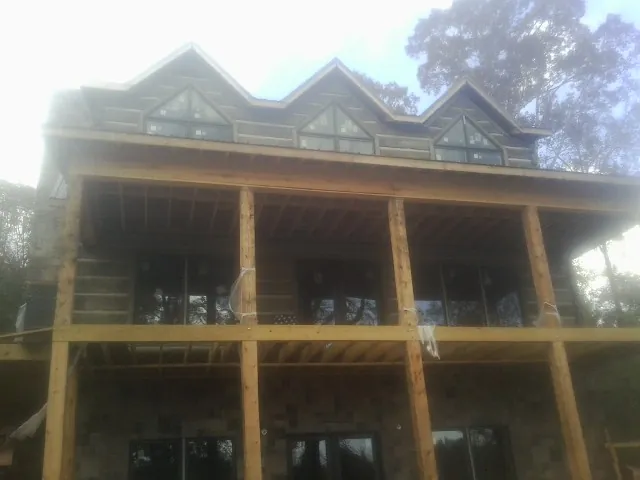 Dormers and porch framing on a large log home under construction — Roof Coating work by our crew in Northvale