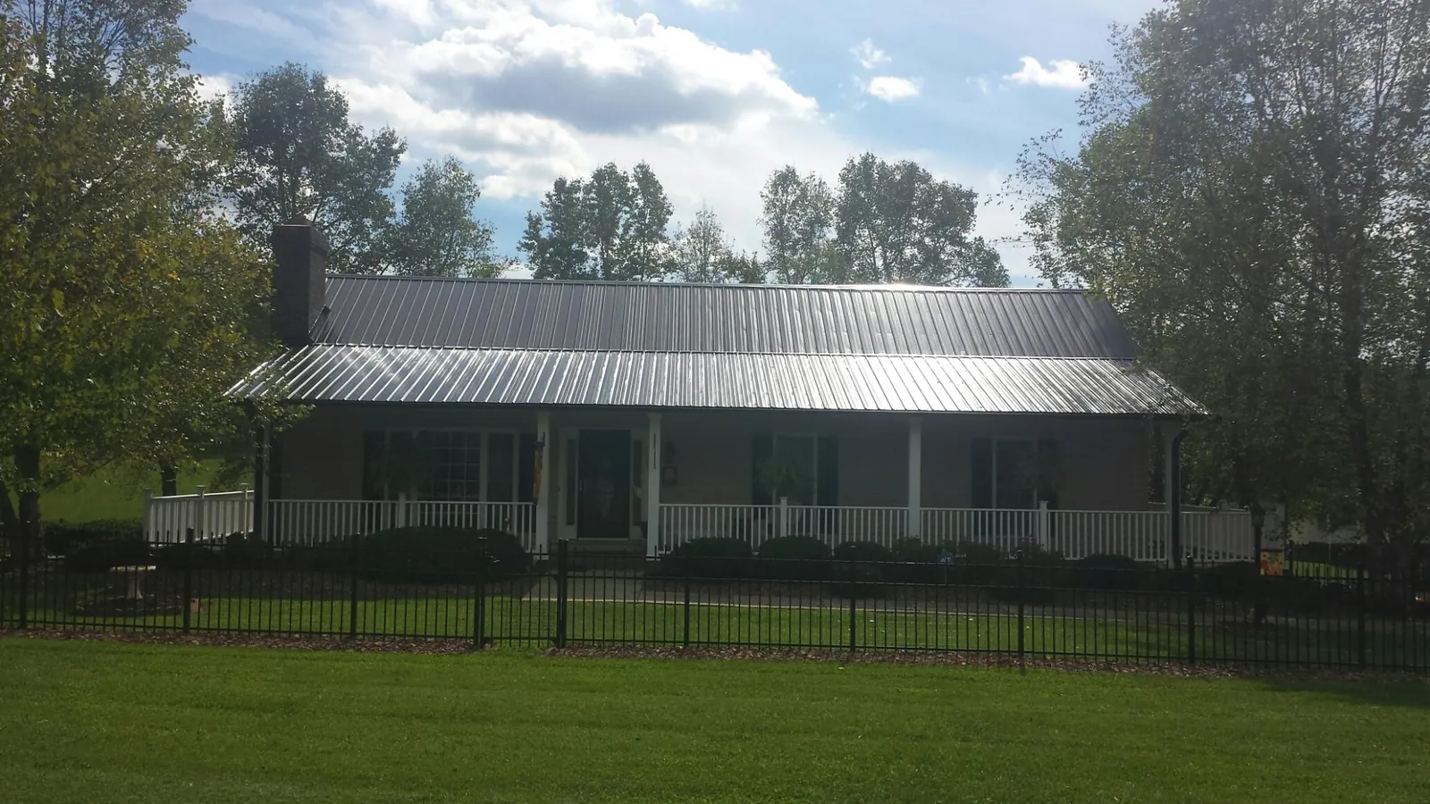Gray metal roof on a brick ranch with a full width front porch — Gutter Guard Installation work by our crew in Northvale