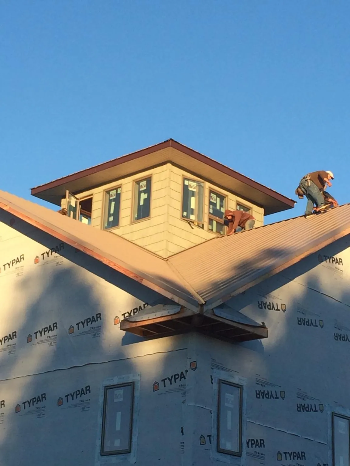 Roofers working around a rooftop cupola on a new metal roof at sunset — Roof Waterproofing in Northvale by Roofing Brothers